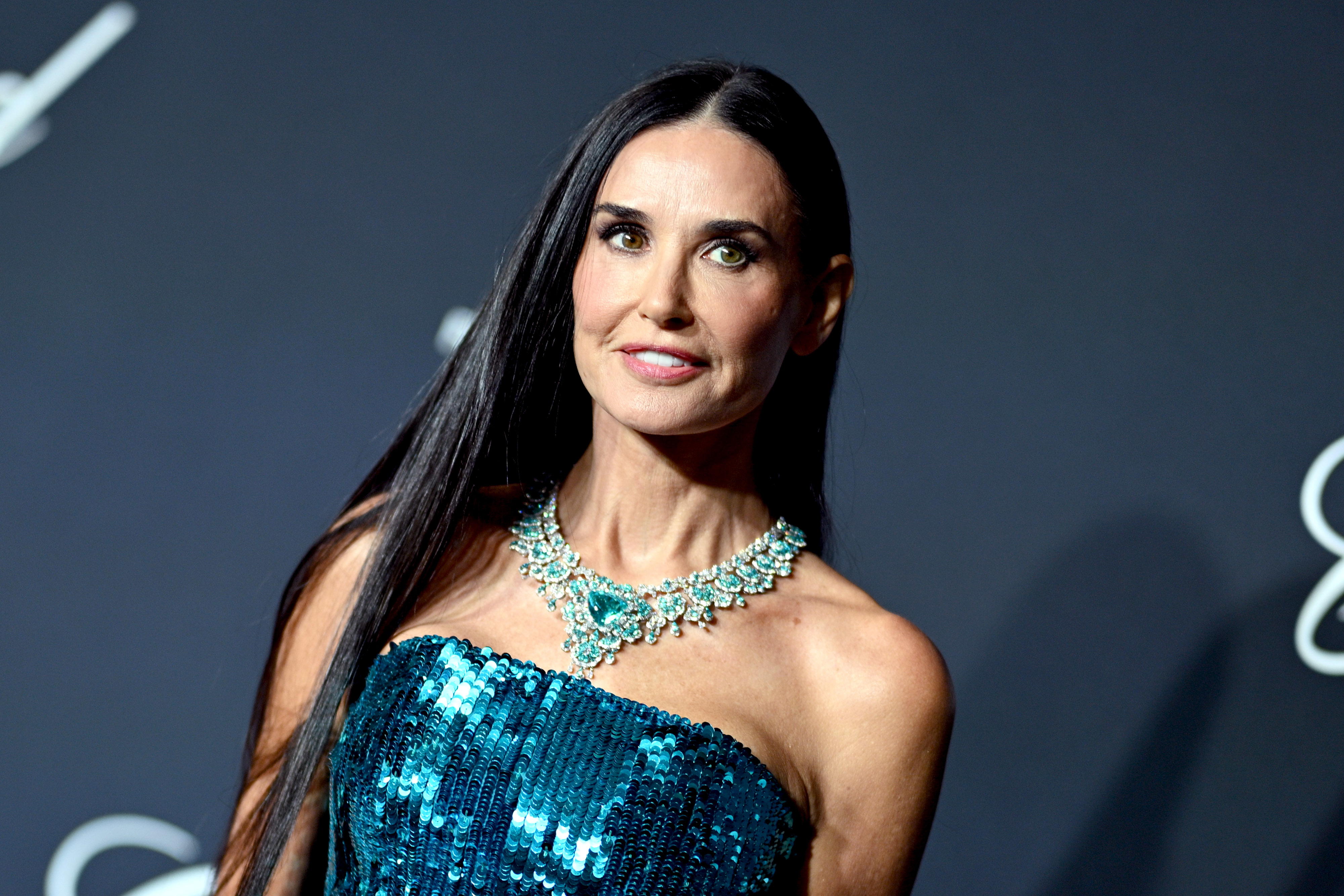 Demi Moore on the red carpet wearing a strapless, sequined dress with a sparkling statement necklace
