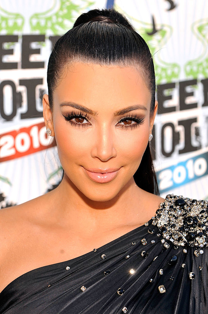 Kim Kardashian at the 2010 Teen Choice Awards in an elegant one-shoulder dress embellished with sparkling details, wearing heavy makeup with noticeably bright under-eyes