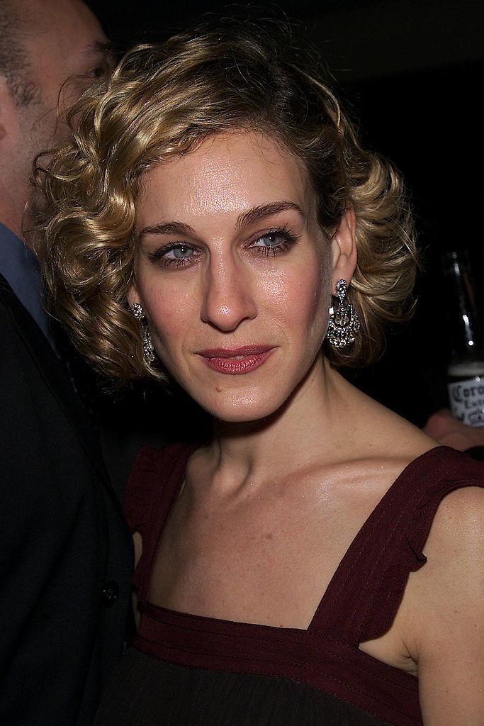 Sarah Jessica Parker with wavy, short hair and wearing a sleeveless dress, standing at an event