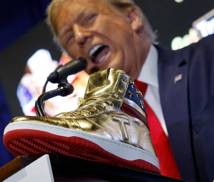 Donald Trump speaks at a podium with a gold and red sneaker with his initials &quot;T&quot; displayed prominently in the foreground