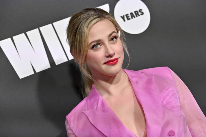 Lili Reinhart wears a stylish suit jacket on the red carpet, posing in front of a backdrop that has "Wired 25 Years" written on it