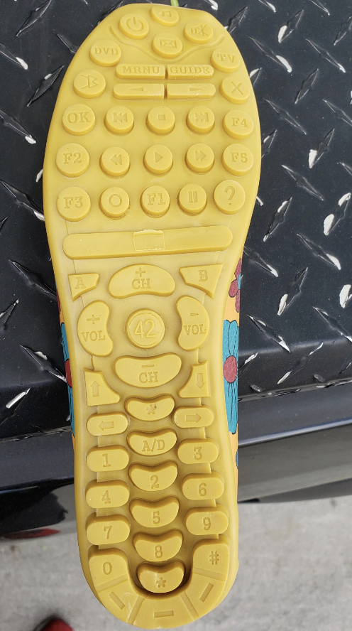 Shoe sole resembling a remote control with various symbols and buttons, including volume, channel, and number buttons, along with F1-F12 function keys