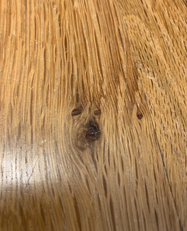 A wooden surface with a knot that resembles a human-like face within the grain texture