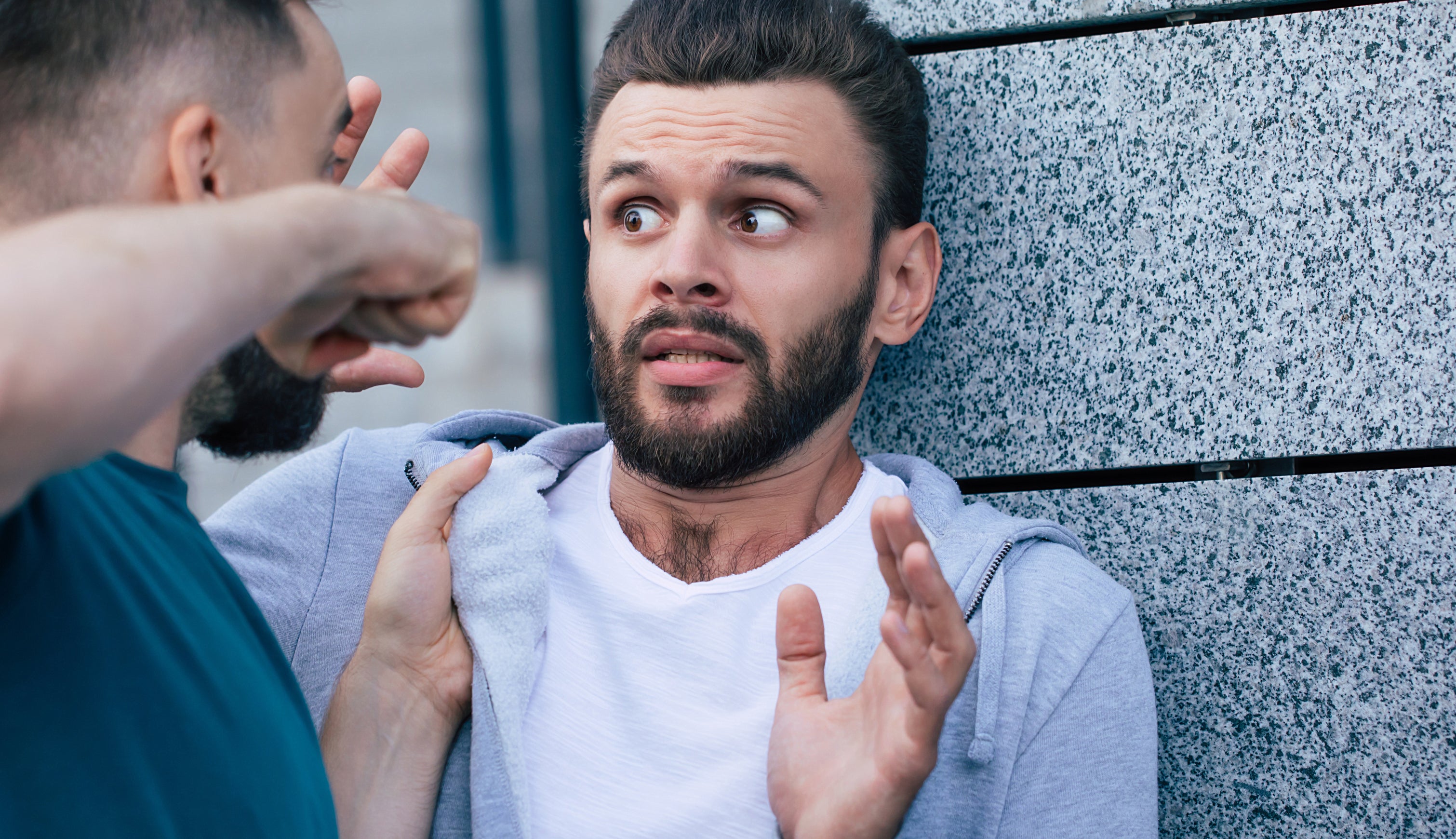 Two men in a confrontation; one looks fearful and defensive, while the other appears aggressive with a raised fist