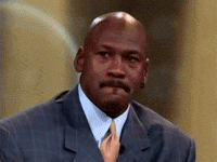 Michael Jordan in a suit laughs and wipes a tear from his eye in an emotional moment