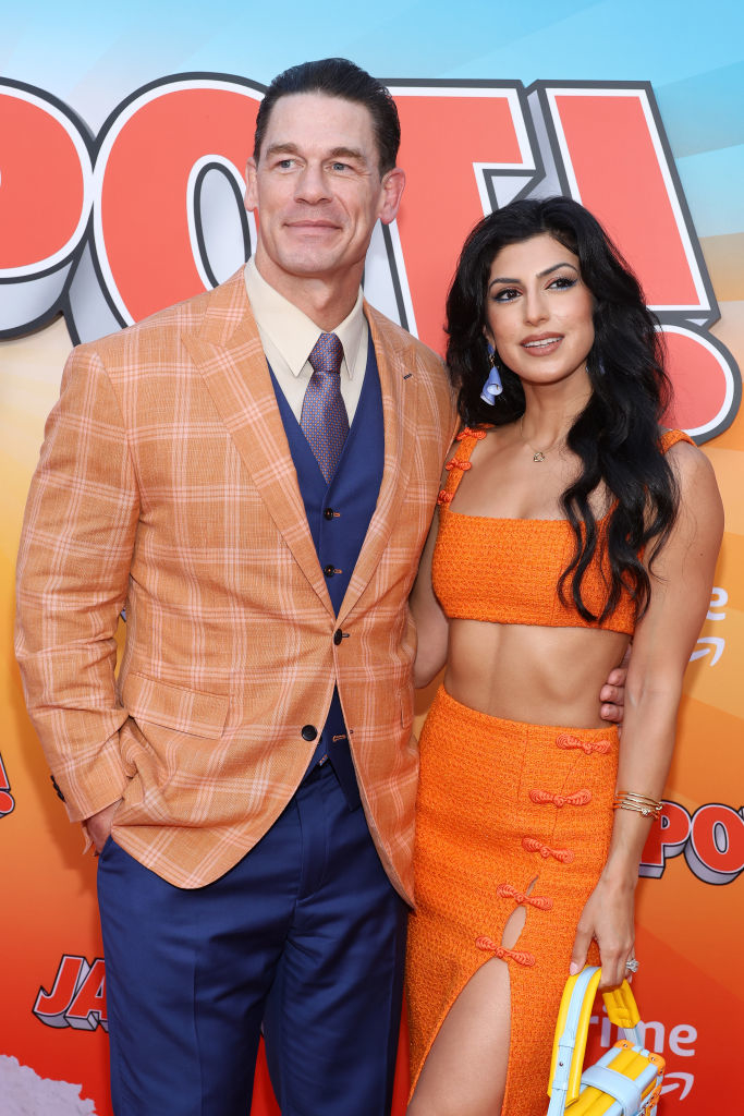 John Cena, in a plaid suit, and Shay Shariatzadeh, in a crop top and skirt, pose together at a movie premiere