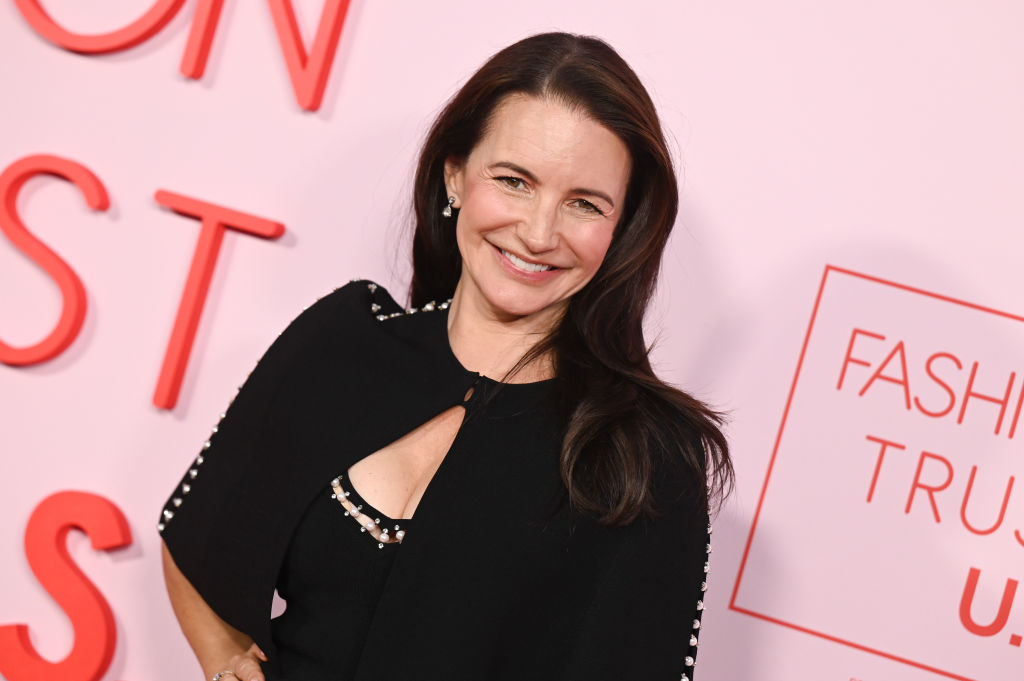 Kristin Davis on the red carpet in a stylish black dress with a cape