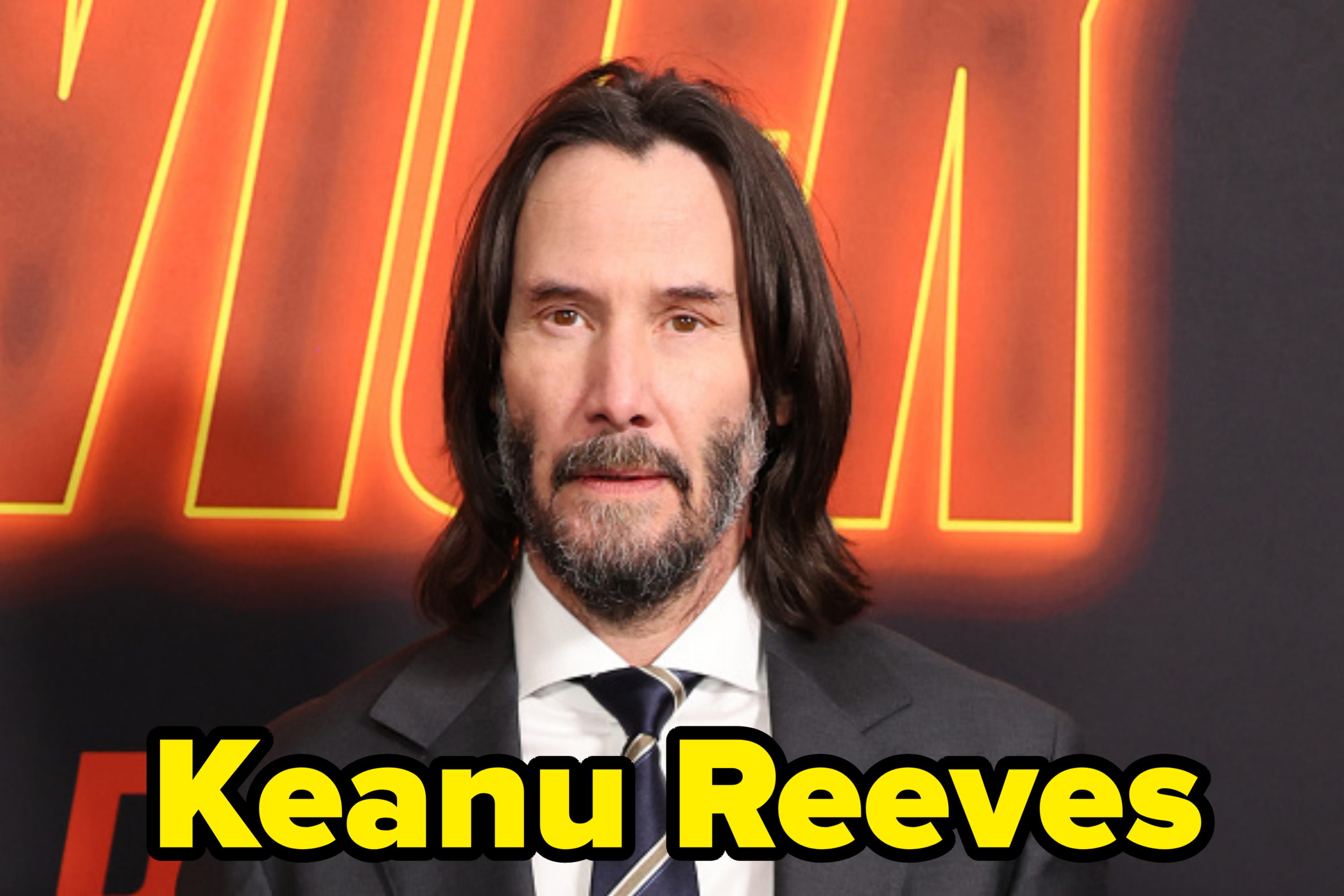 Keanu Reeves poses in a suit and tie at an event with a &quot;John Wick&quot; backdrop