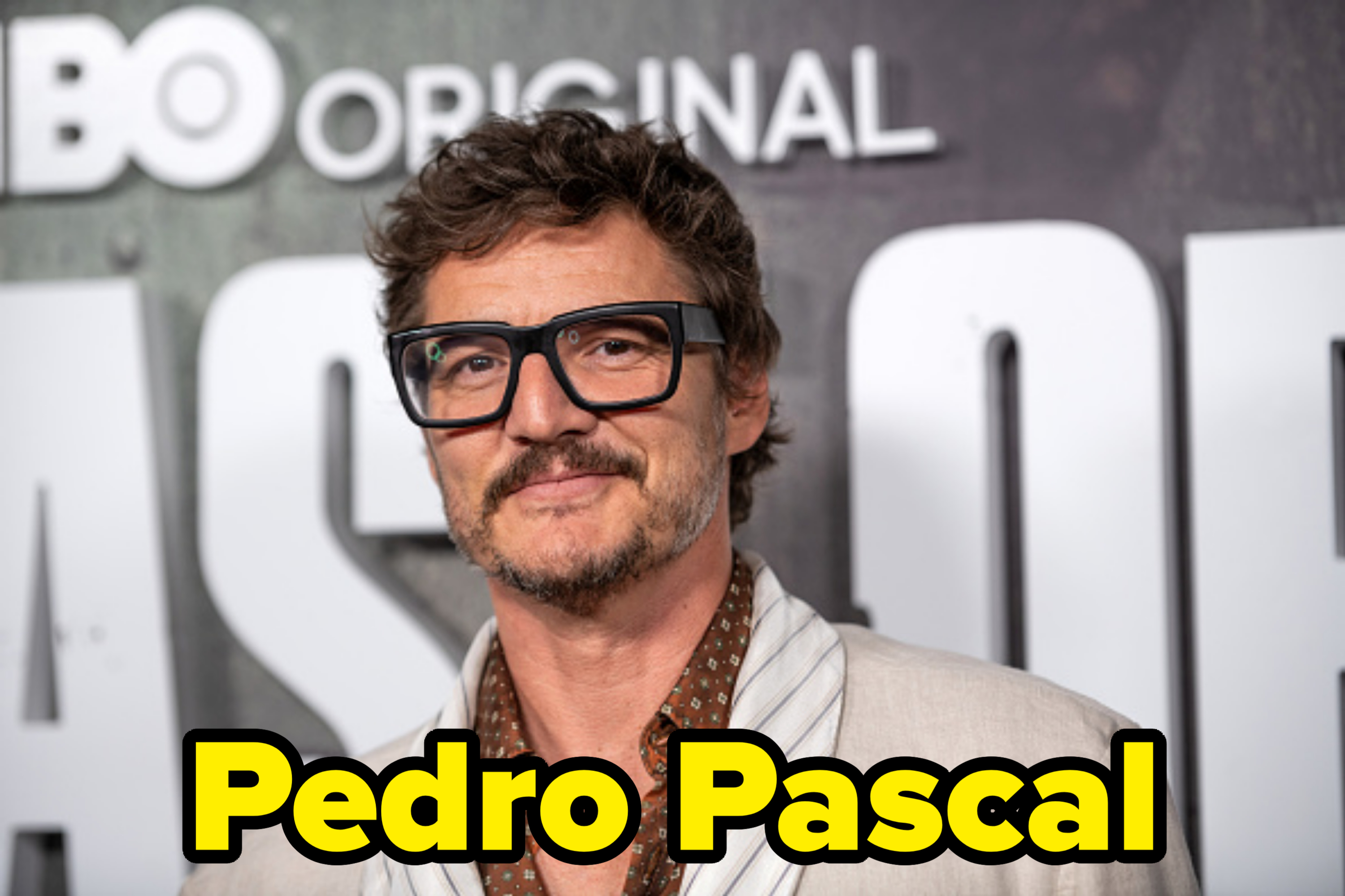 Pedro Pascal at an HBO Original event, wearing a beige blazer over a patterned shirt and thick-framed glasses