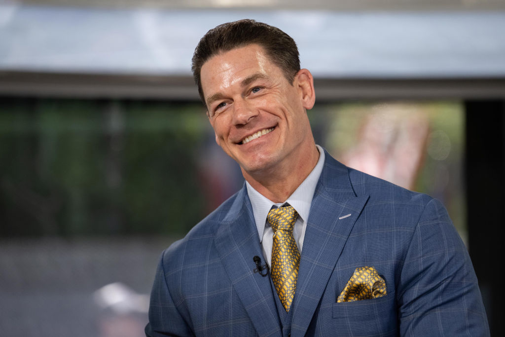 John Cena, smiling in a suit and patterned tie, during an interview or public appearance