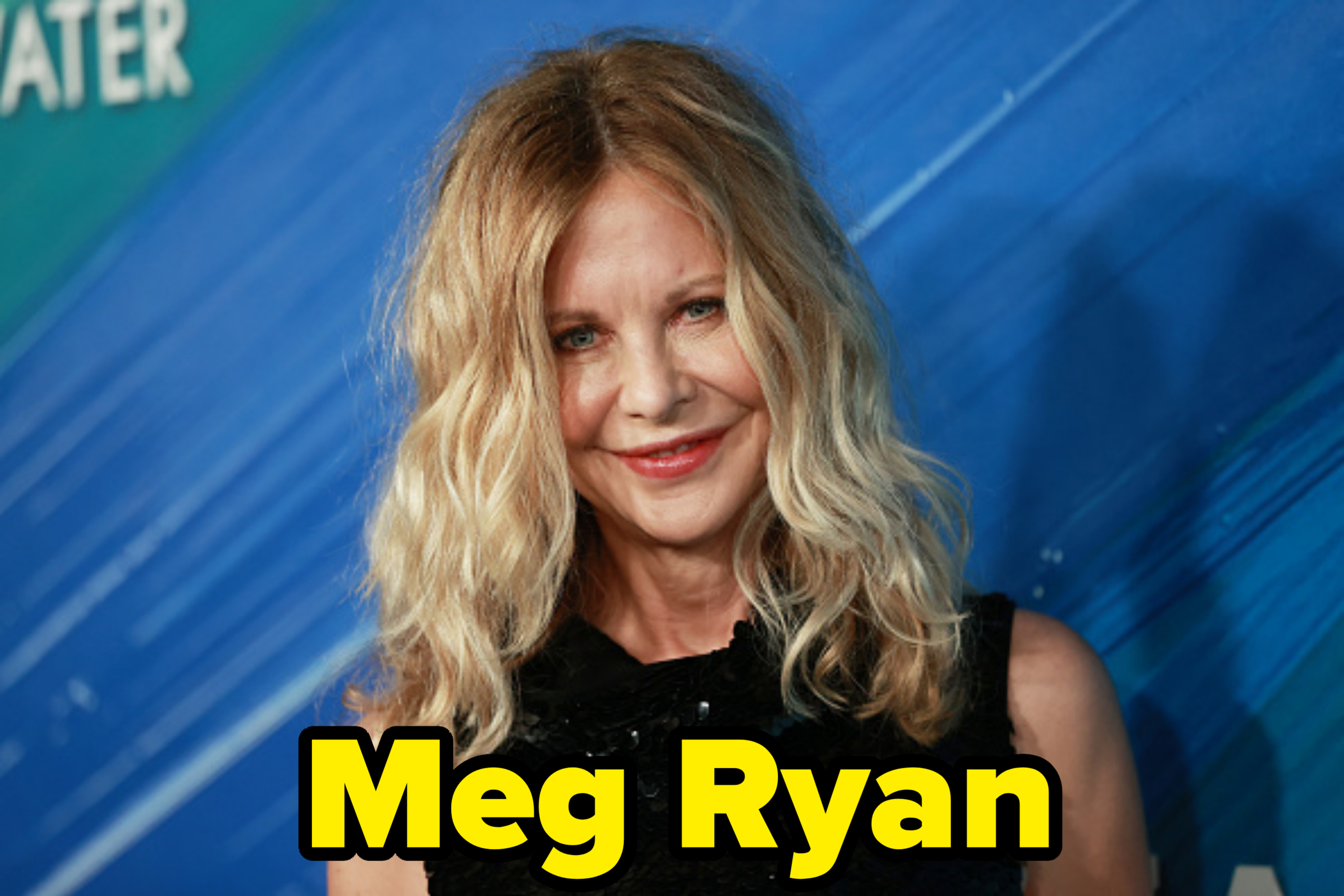 Meg Ryan poses against a blue backdrop, wearing a black top. She has wavy blonde hair and smiles at the camera