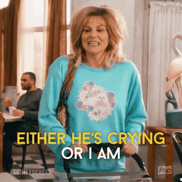 A woman in a blue sweater with text overlay: "Either he's crying or I am."