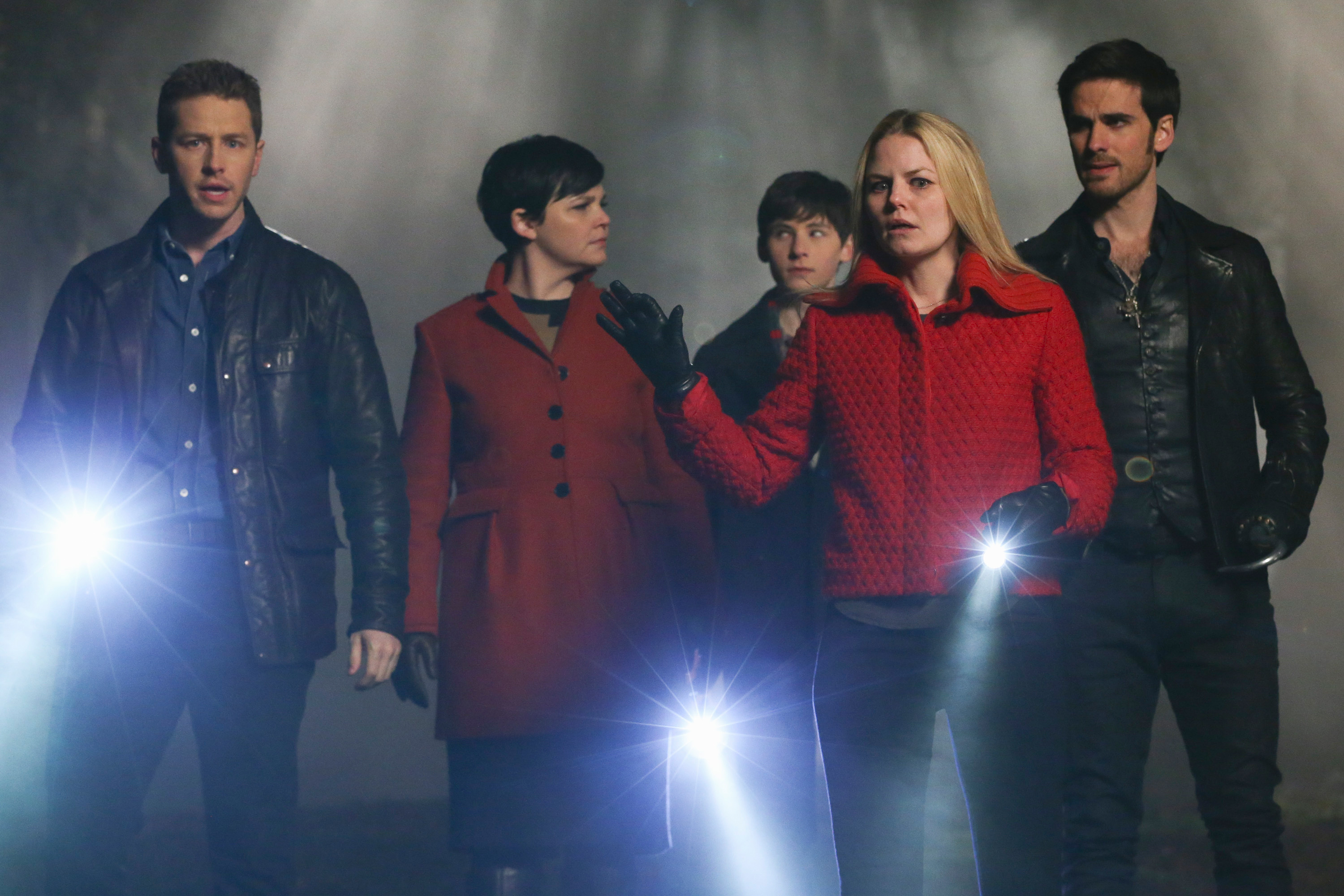 Josh Dallas, Ginnifer Goodwin, Jared S. Gilmore, Jennifer Morrison, and Colin O'Donoghue holding flashlights, dressed in modern jackets, on a misty set