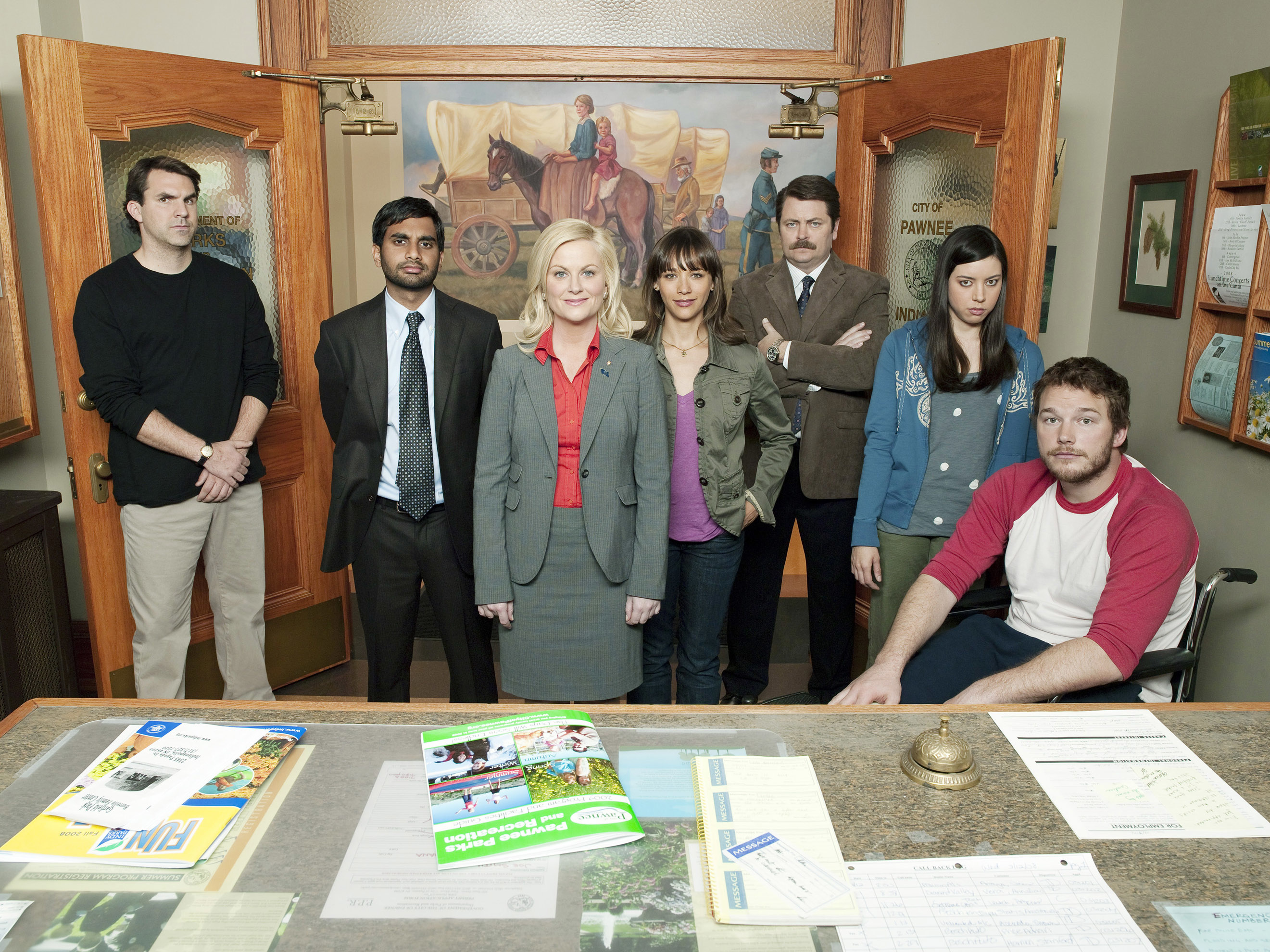 The image features cast members of Parks and Recreation: Nick Offerman, Amy Poehler, Chris Pratt, Aubrey Plaza, Rashida Jones, Aziz Ansari, and Adam Scott