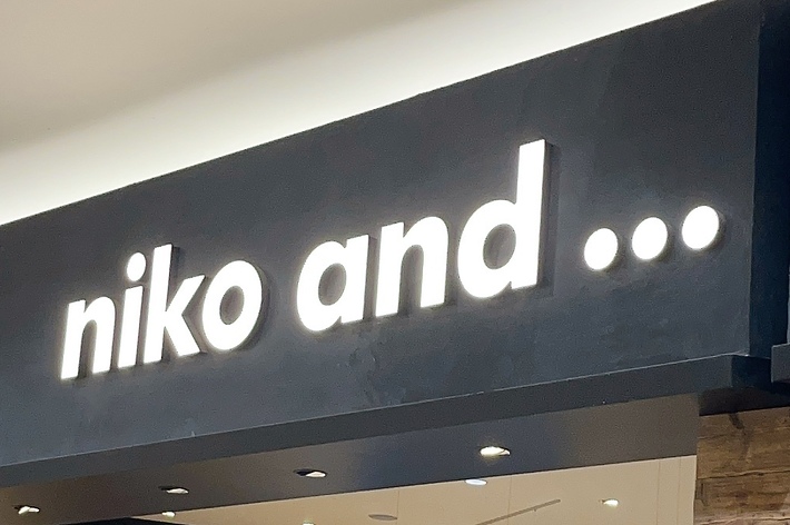 Storefront of &ldquo;niko and …&rdquo; with various clothing and home goods displayed. Inside a shopping mall