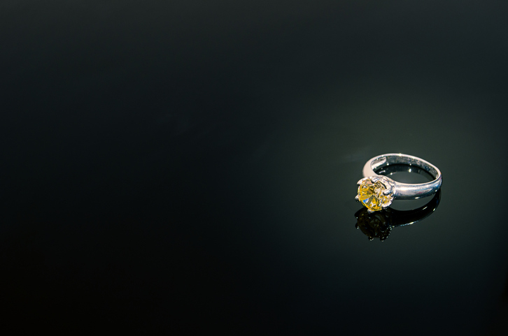 A diamond ring placed against a dark background, showcasing its reflective surface and intricate design