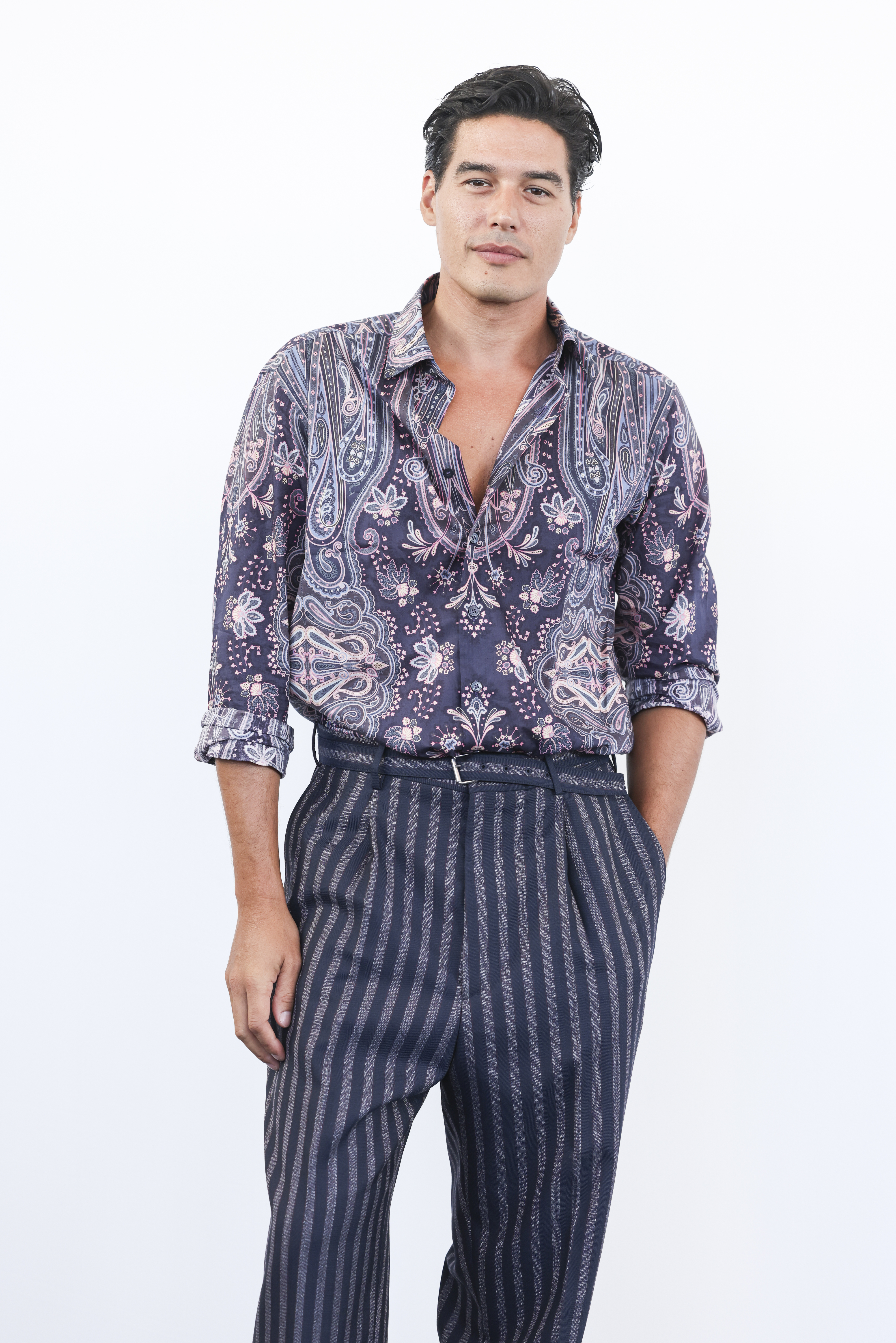 Cristiano Caccamo wearing a paisley shirt and striped pants, posing confidently