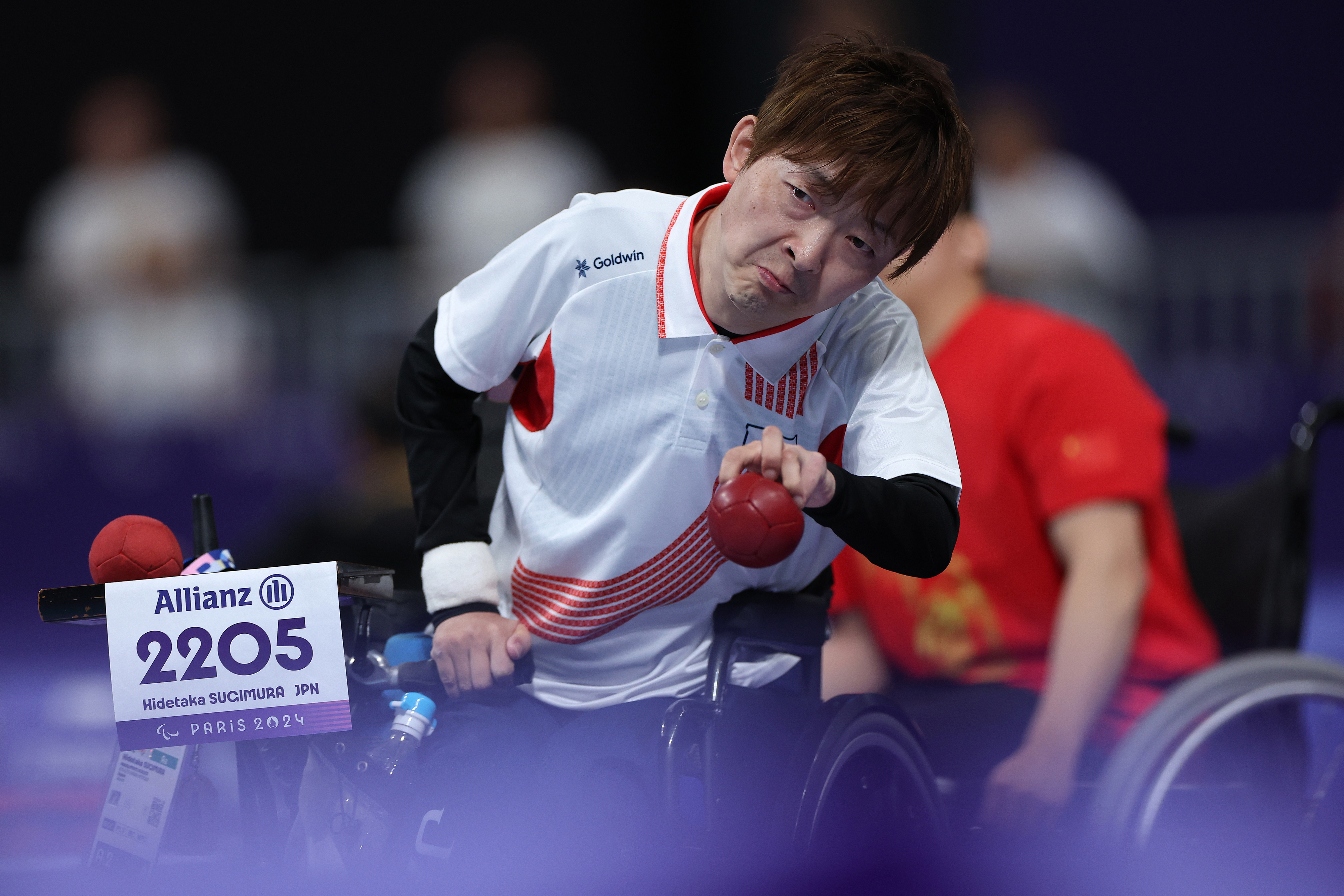 Hidetaka Sugimura, in a wheelchair, competes in a boccia event at the Paralympics. He is wearing a white sports jersey with the number 2205