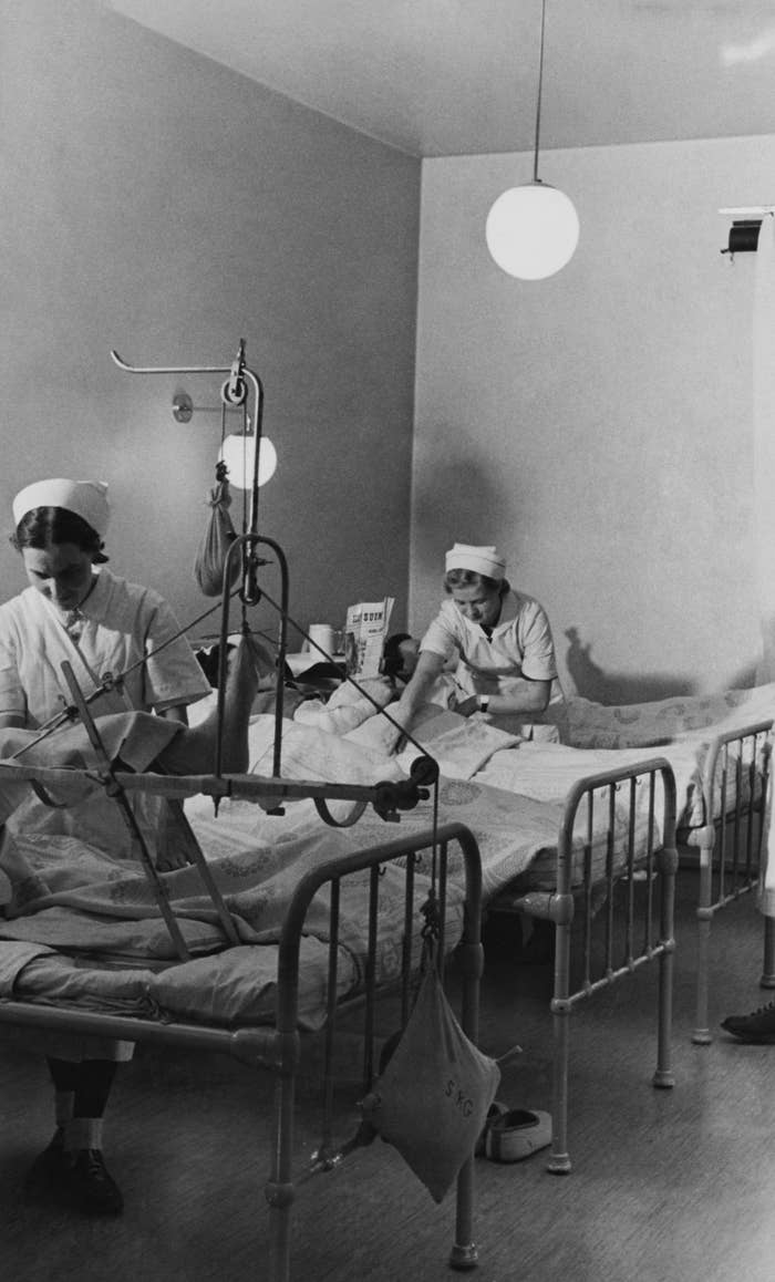 Nurses attend to patients in a hospital room, with medical equipment around the beds