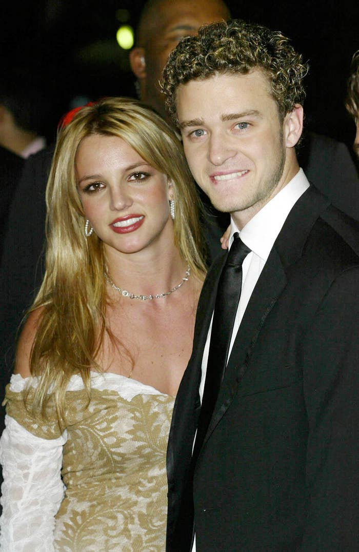 Britney Spears in an off-shoulder dress and Justin Timberlake in a suit smile for the camera at a red carpet event
