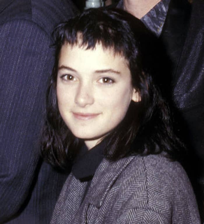 Winona with medium-length dark hair in a blazer and shirt, smiling softly at the camera in a close-up shot