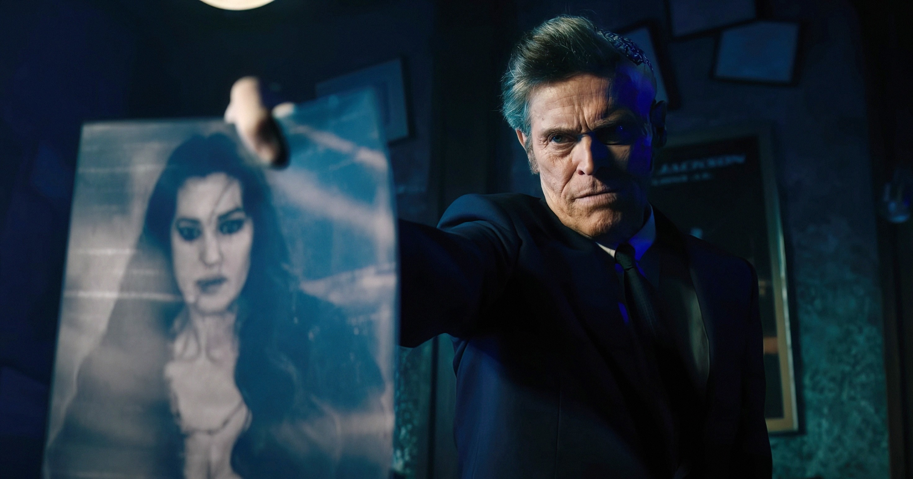 Willem Dafoe holds up a blurred image of Monica Bellucci