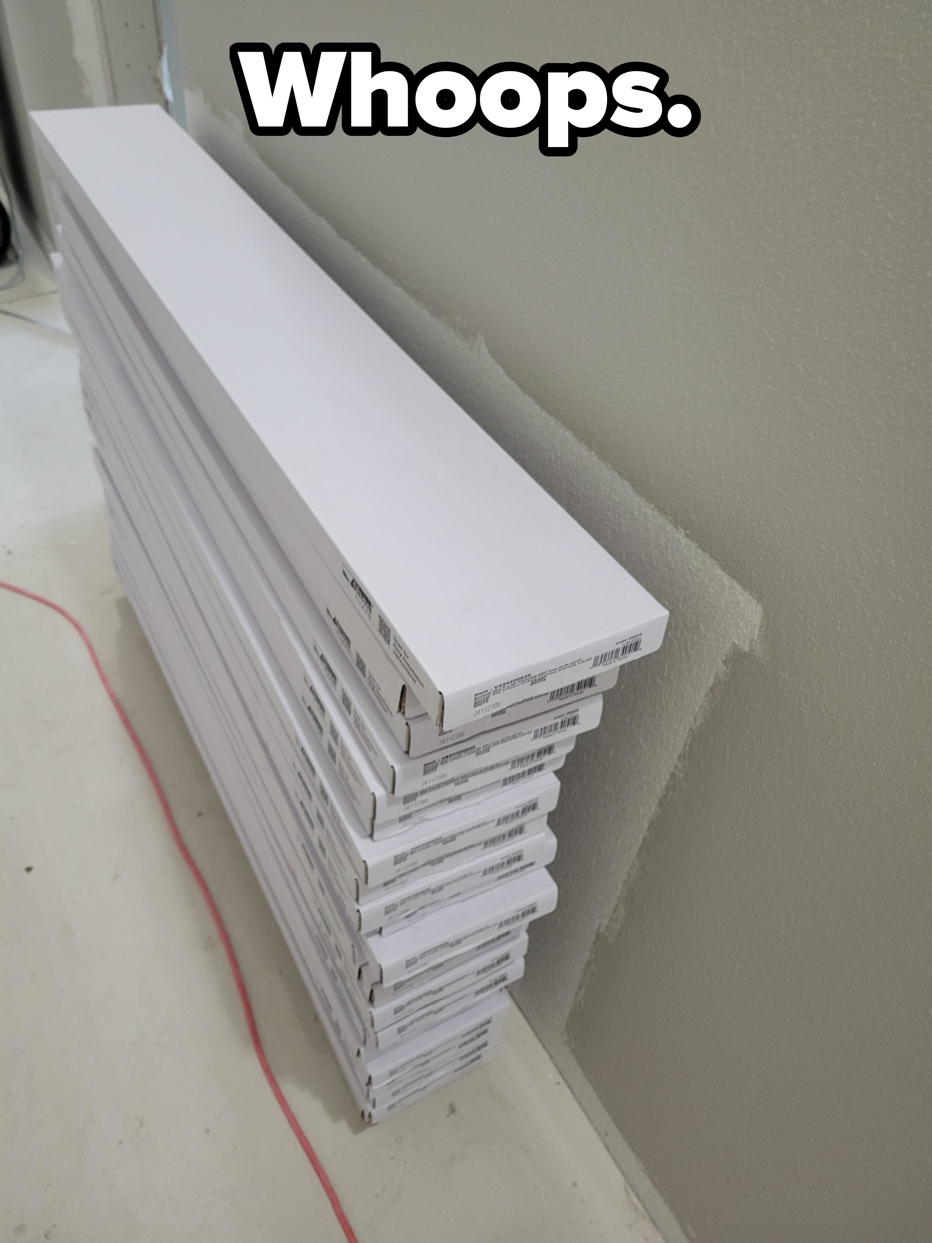 Stacked flat-pack boxes leaning against a wall, possibly DIY furniture or materials for home improvement. No persons or text present