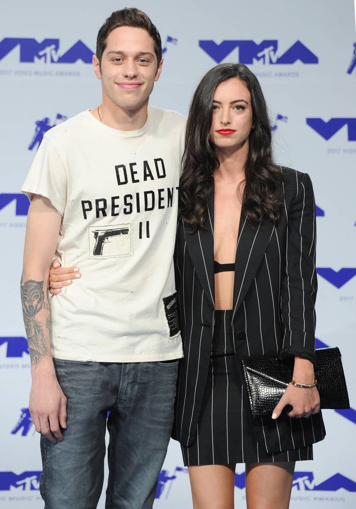 Pete Davidson in a casual shirt and jeans with Cazzie David in a pinstripe suit dress, posing together at a MTV event