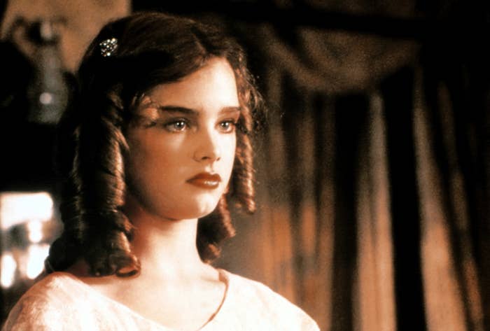 A young Brooke with curled hair, wearing a classic style, gazes intently in a scene from Pretty Baby