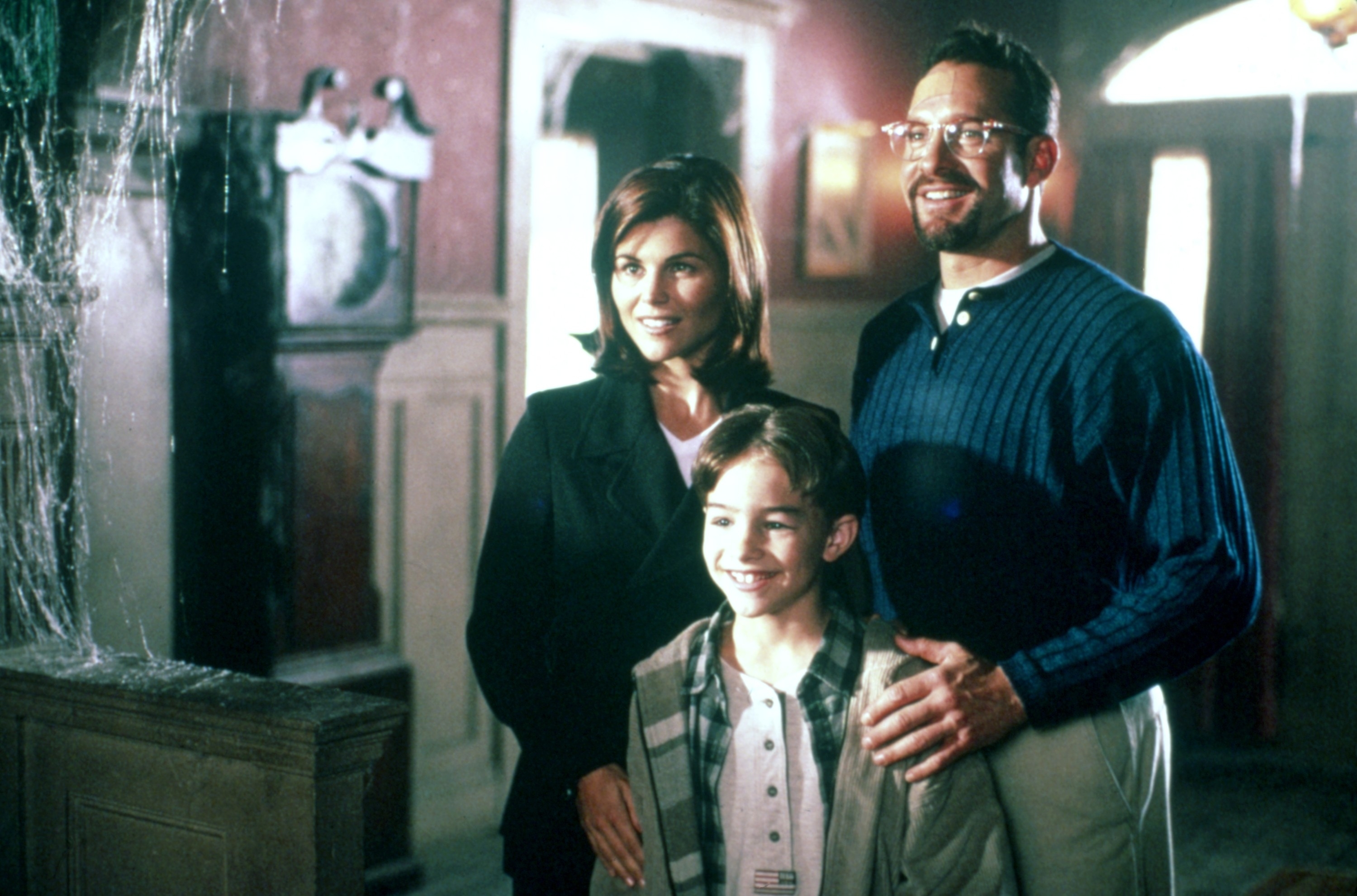 Teri Hatcher, Zachery Ty Bryan, and Tim Allen in a scene from a TV show. They are standing together in a warmly lit home setting with smiles on their faces