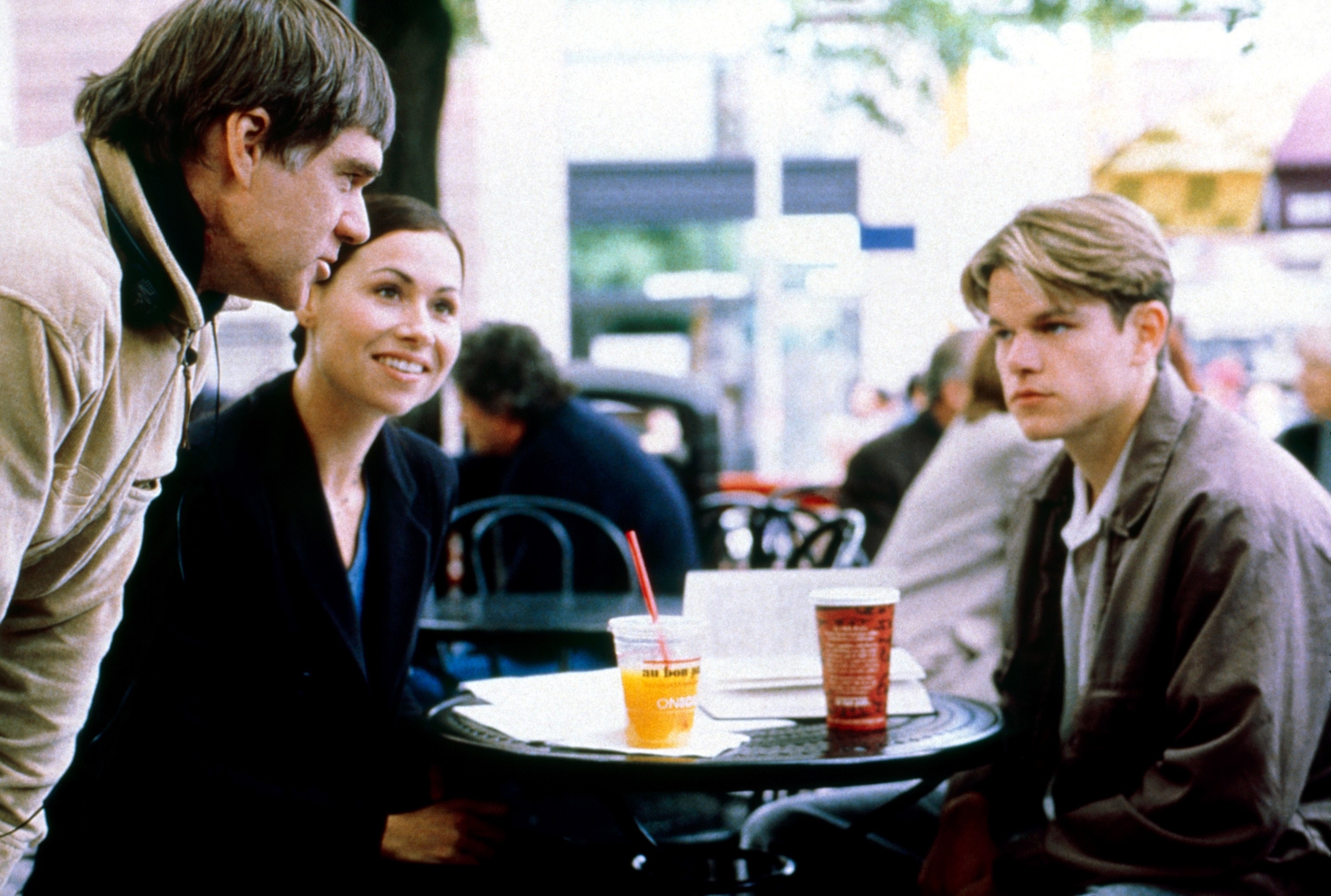 Matt Damon, Minnie Driver, and Robin Williams are sitting at an outdoor café table, engaging in conversation