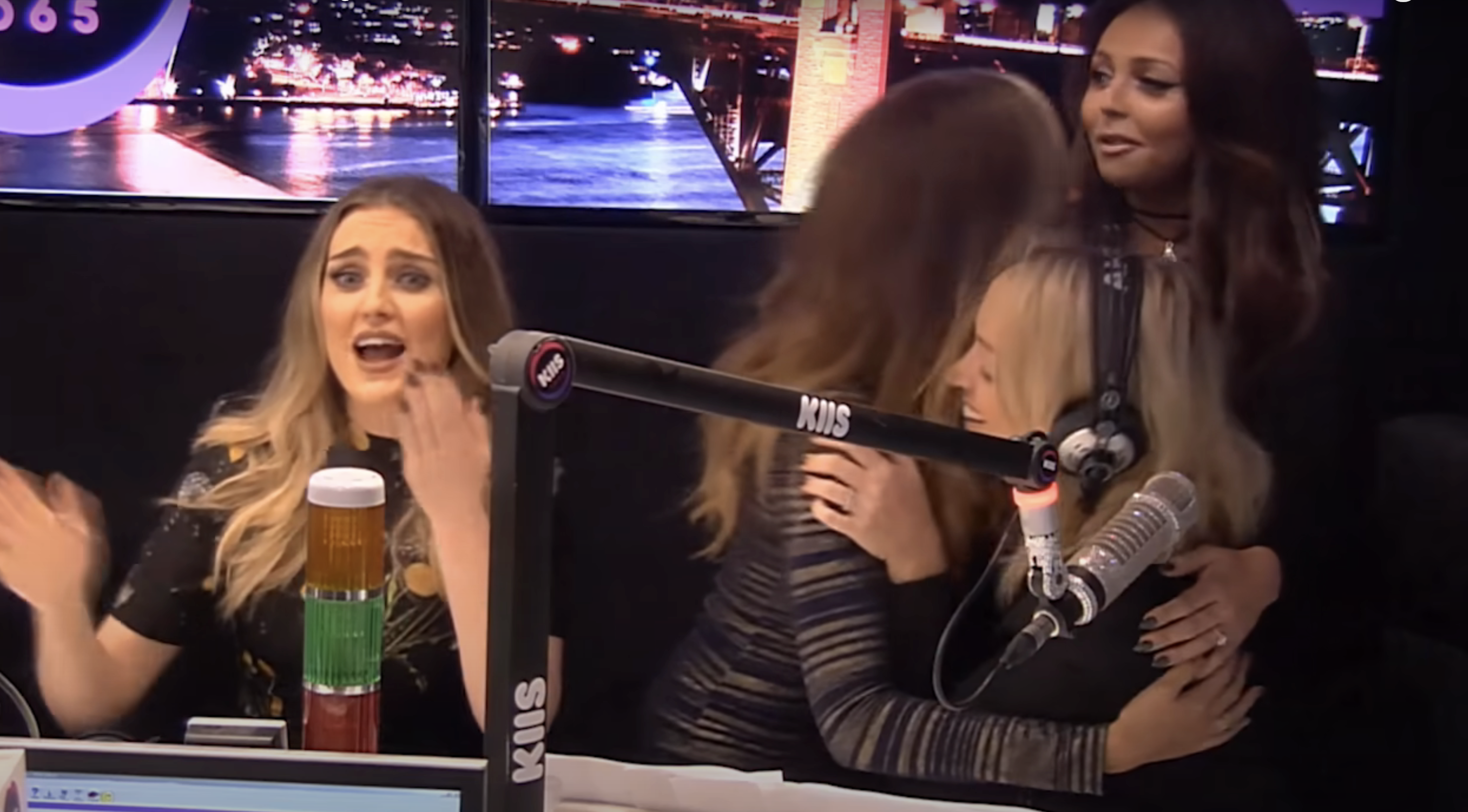 Perrie Edwards, Jade Thirlwall, and Jesy Nelson chat and hug in Jackie O in a radio studio with microphones