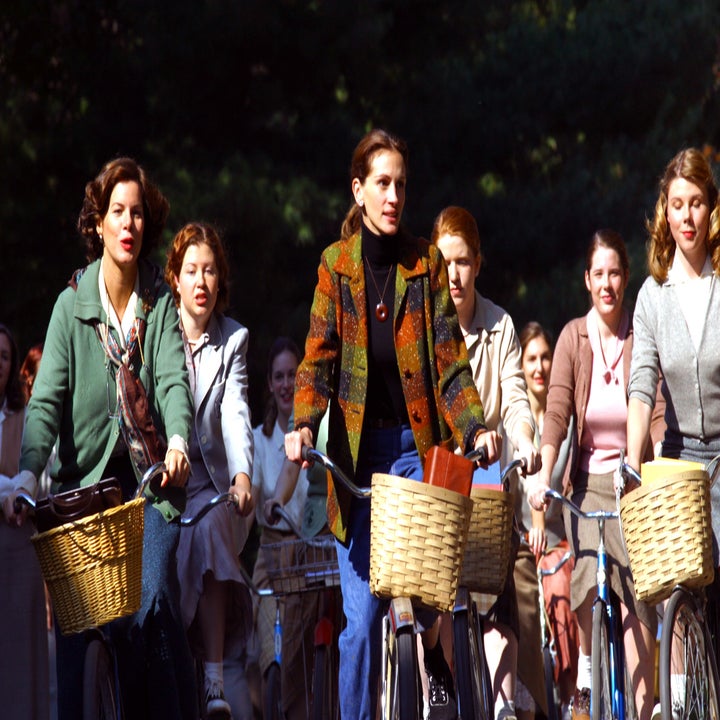 Julia Roberts riding a bike with a group of high school girls, all on bikes with baskets, in a park. The scene is lively and evokes a sense of camaraderie