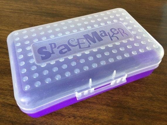 Plastic Spacemaker pencil box with a dimpled surface and purple bottom, placed on a wooden surface