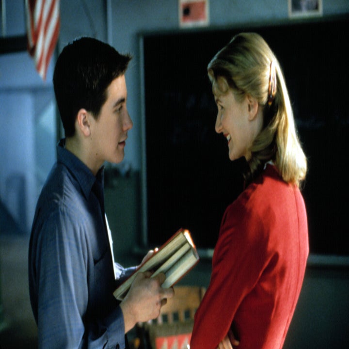 Jake Gyllenhaal and Laura Dern stand facing each other; Jake is holding a book and Laura is smiling at him in a classroom setting