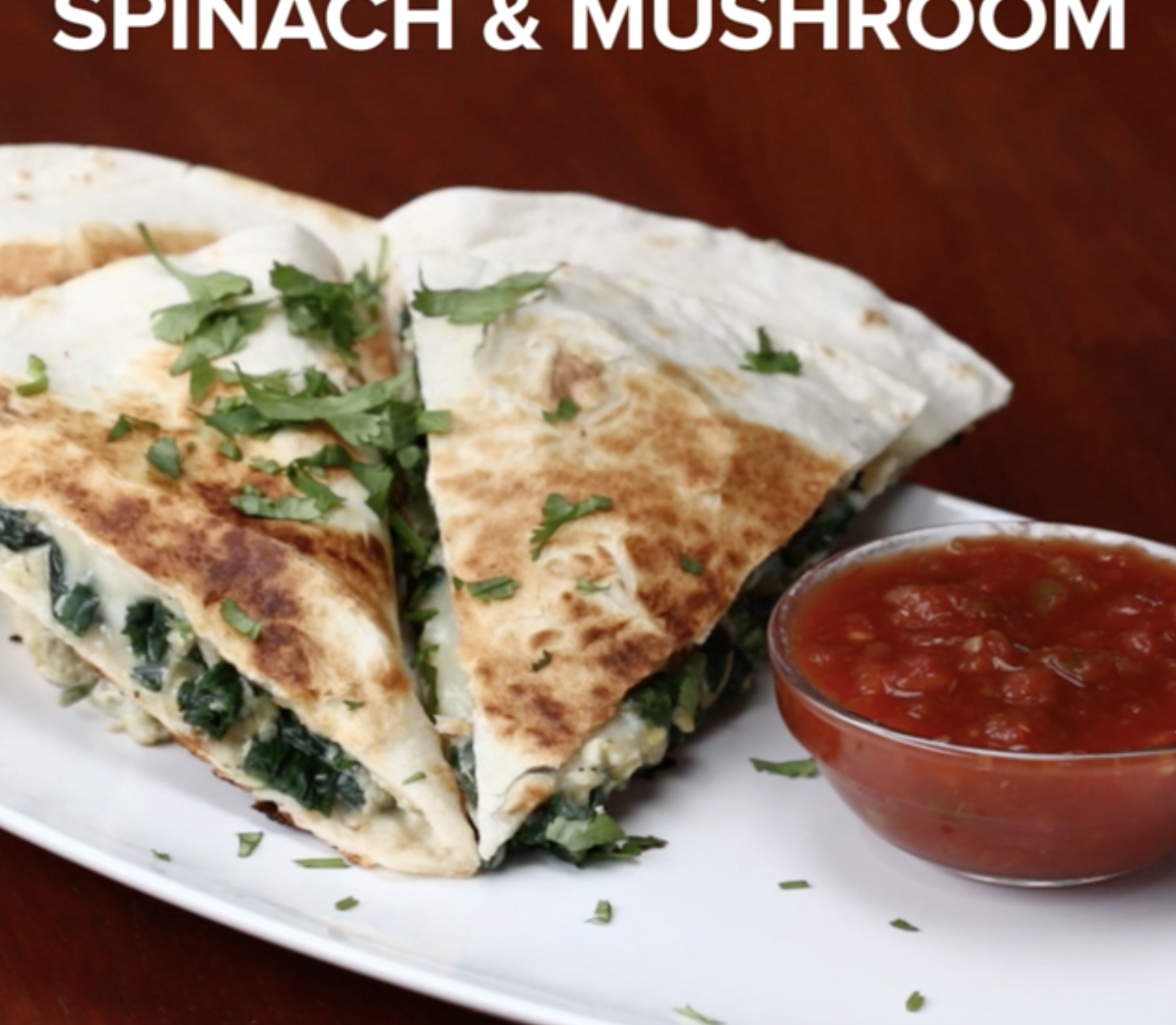 A plate with spinach and mushroom quesadilla slices garnished with herbs, accompanied by a small dish of salsa. Text: &quot;Spinach &amp;amp; Mushroom&quot;