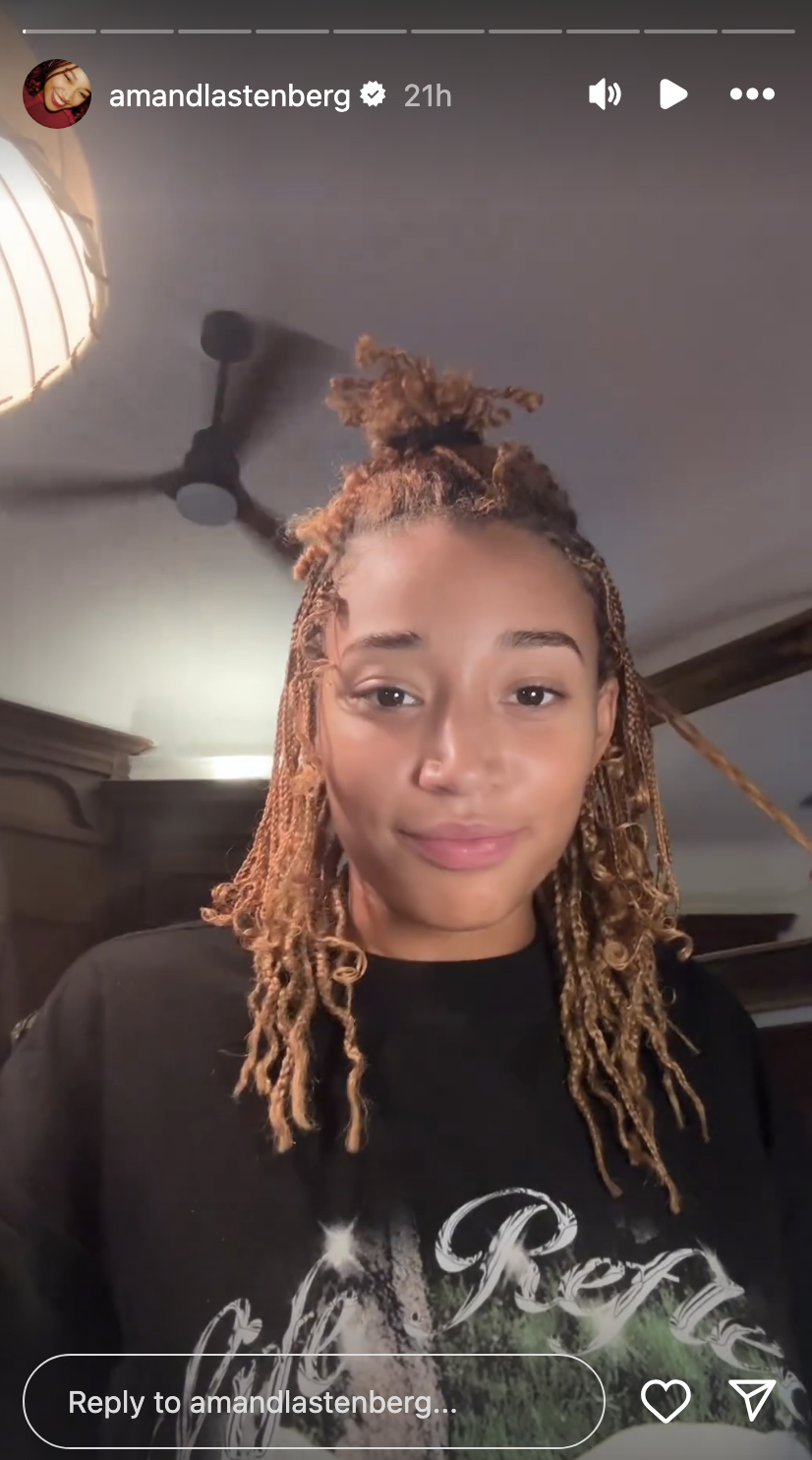 Amandla Stenberg shares a selfie on Instagram Stories, with a light smile and her hair styled in locks. She wears a casual, dark sweatshirt