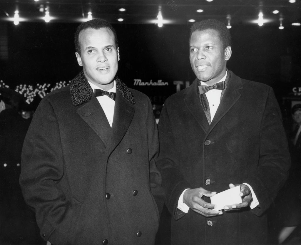 Harry Belafonte and Sidney Poitier, in formal attire with bow ties and overcoats, attend an event together under bright lights