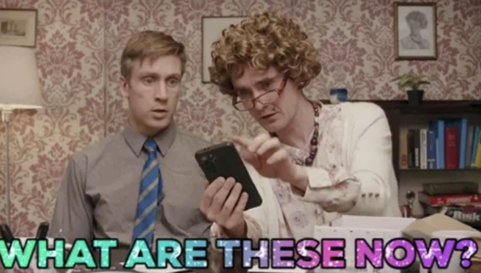 Two people look at a phone with confusion. Text overlay reads: "What are these now?"