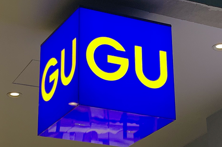 A blue and yellow &ldquo;GU&rdquo; sign hangs from the ceiling in a shopping area