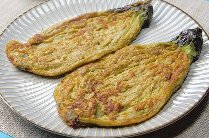 お皿に盛り付けられた焼きナスと小さなケチャップの入った白い器が見えます。