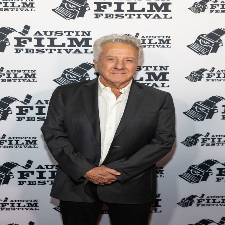 Dustin Hoffman at the Austin Film Festival, wearing a classic dark suit with a white dress shirt, standing in front of a festival step-and-repeat backdrop