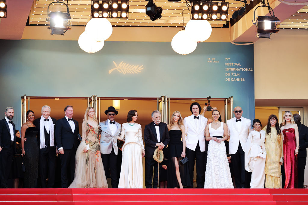 A large group of celebrities stand on the red carpet at the Cannes Film Festival, posing for a photo in elegant formal attire