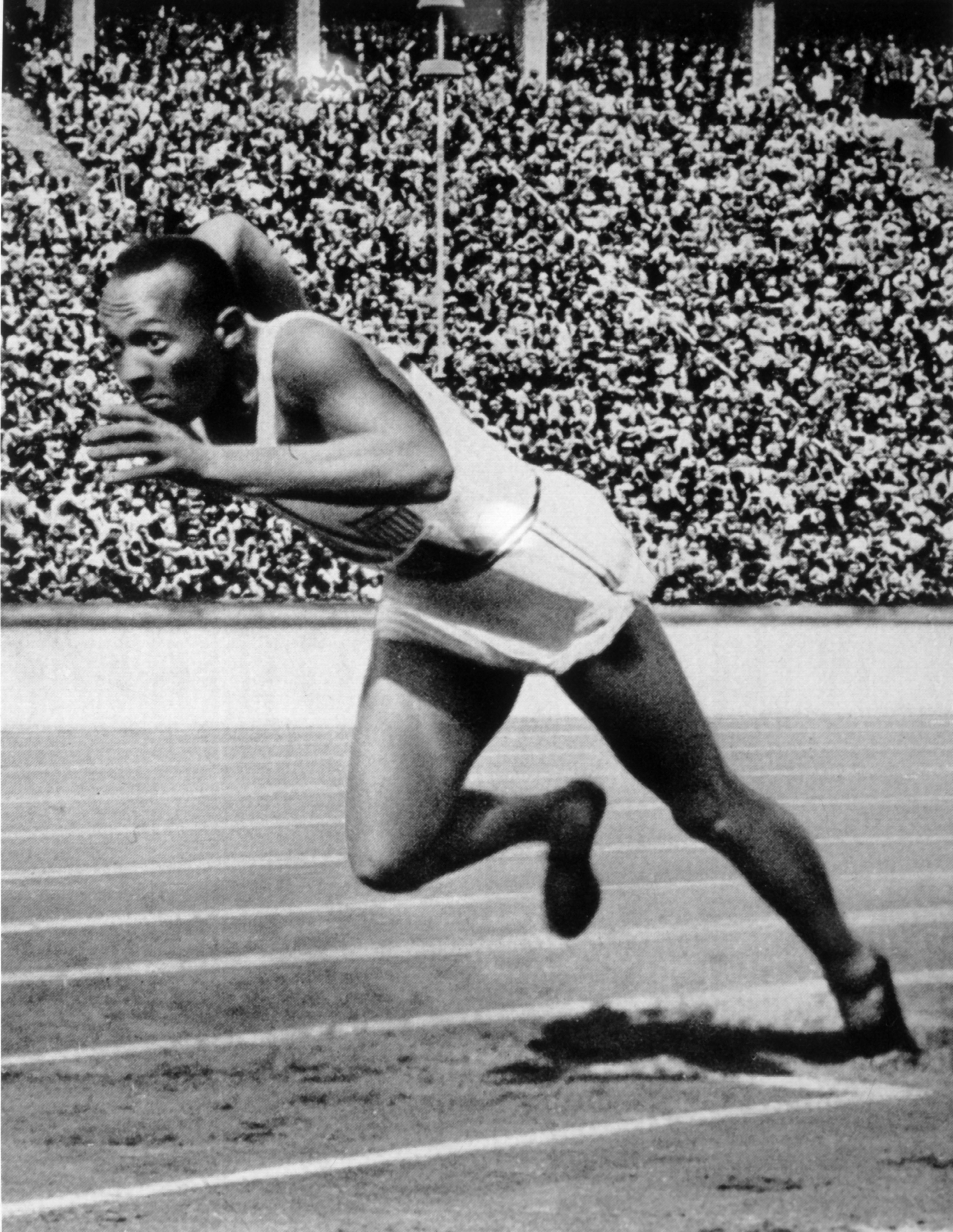 Jesse Owens, in athletic attire, starts a race at a stadium filled with spectators