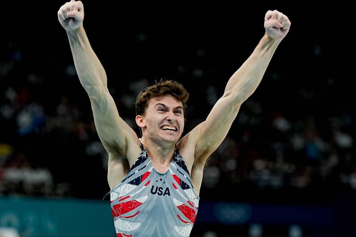 Olympic gymnast Artem Dolgopyat in a leotard with &quot;USA&quot; on it, celebrates with arms raised and fists clenched