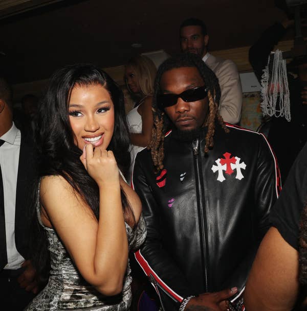 Cardi B, in a shimmering dress, and Offset, in a black jacket with red and white designs, pose together at an event