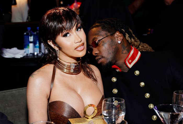 Cardi B and Offset sit together at a formal event, with Cardi B wearing a halter dress and Offset in a military-inspired jacket