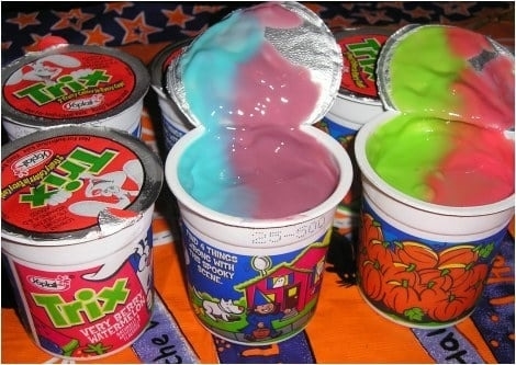Yoplait Trix Yogurts with colorful yogurt inside cups. Two open cups display mixed colors of yogurt, while three sealed cups feature cartoon designs