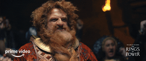 Dwarf from "The Lord of the Rings: The Rings of Power" series on Prime Video cheers, thick beard and detailed armor prominent