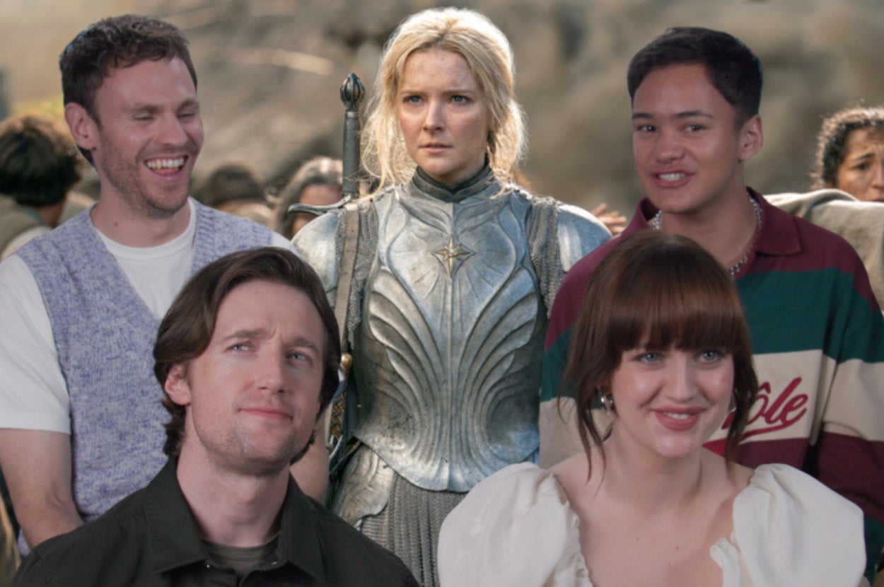 Five people stand together. The middle person wears medieval armor. The others wear casual modern clothing